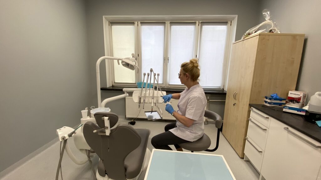 Dentystka przygotowująca narzędzia w nowoczesnym gabinecie stomatologicznym z naturalnym światłem.