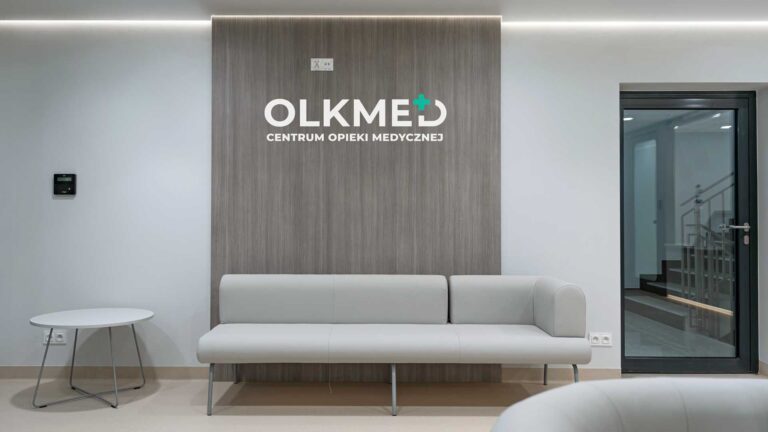 Nowoczesne wnętrze recepcji centrum medycznego OLKMED z minimalistycznym wystrojem i wygodną kanapą.